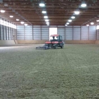 Tractor driving on horse riding arena